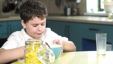 Child has Breakfast in kitchen of the house with corn flakes with milk. Vidéo 133633956