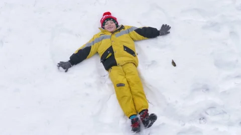 Child has fun making the angel in the snow Stock Footage 146529558