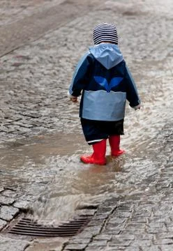 Child has fun with rainwear in the rain Stock Photos