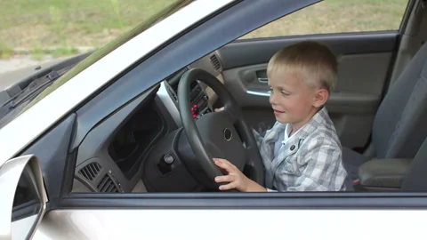 The child is having fun and playing behind the wheel in dad's car. Stock Footage 115152772