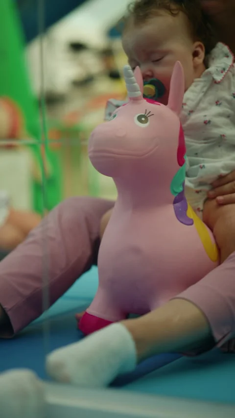 Child having fun bouncing on a pink inflatable unicorn toy, enjoying active Vídeo Stock 343309333