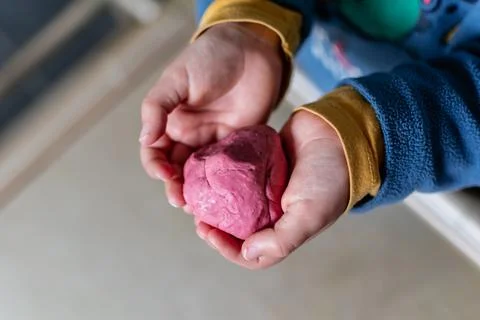 Child having fun modeling salt dough, authentic activity with natural pink .. Foto stock