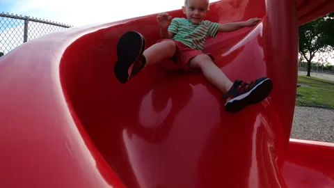 Child is having fun outside and sliding down the slide. Stock Footage 135310795