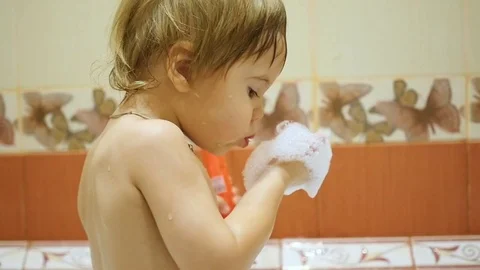 Child having fun playing with foam in the bath. Blows foam with palms 库存影片 70671901