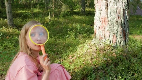 Child having fun playing with a magnifying glass outdoors Video stock 293949899