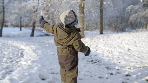 Child having fun playing in the snow near a forest Stock Footage 158671396