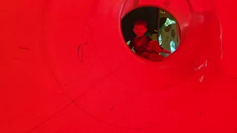 Child is having fun sliding down the tube on the playground. Smiling boy Vídeos de archivo 337419134