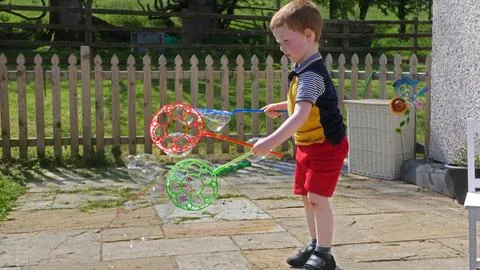 A child having fun with Soap Bubbles in a garden in summer Foto stock
