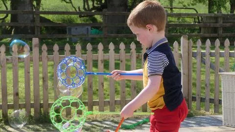 A child having fun with Soap Bubbles in a garden in summer Foto stock