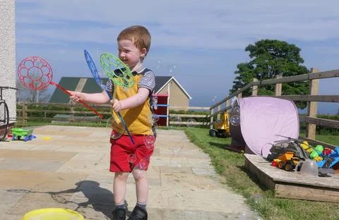 A child having fun with Soap Bubbles in a garden in summer Stock Photos