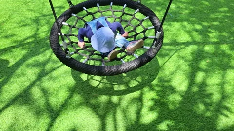 Child having fun as they swing on the summer playground. Happy childhood and Stock Footage 337419297
