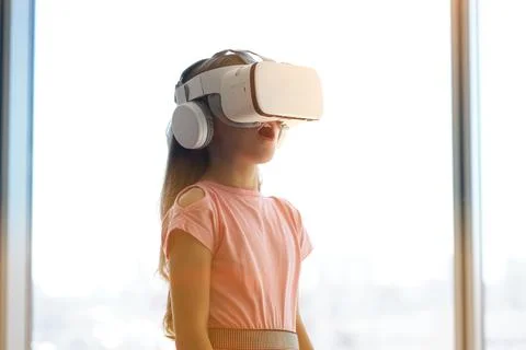 A child is having fun in white virtual reality glasses, standing against the Fotos de archivo