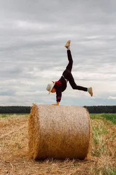 A child on a haystack does a handstand. carefree childhood in the country 库存照片