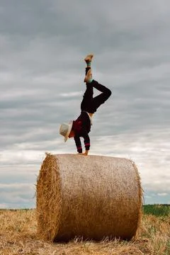 A child on a haystack does a handstand. carefree childhood in the country, su Fotos de archivo