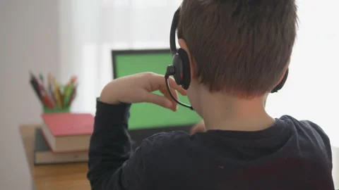Child with headphones sitting with back, computer with green screen, pencils Stock Footage 150730583