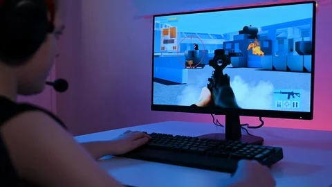 Child with headset plays first person shooter video game on computer Stock Footage 100724994
