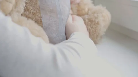 A child with her teddy bear both in masks stay by the window in the room Stock Footage 127579379