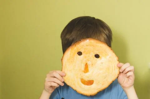 A child hidden behind a cookie in shape of a mug with a smile. children's cre Stock Photos