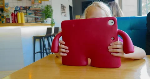 Child hiding face behind red tablet case Stock Footage 264929071