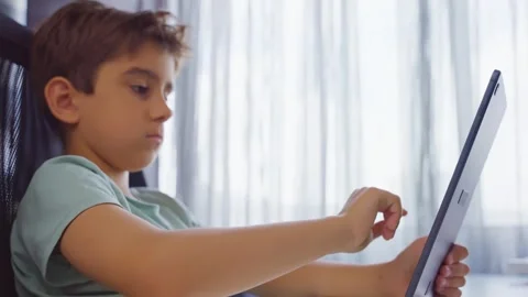 Child holding and tapping on a tablet indoors. Close up. Side view Stock Footage 255509388