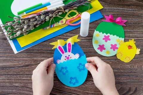 A child is holding an Easter egg gift with a chicken and Easter bunny toy. Stock Photos
