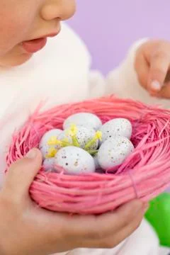 Child holding Easter eggs in pink nest Stock Photos