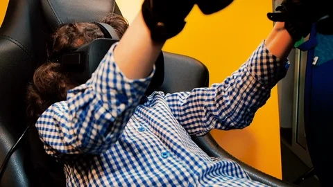 A child holding a gaming computer wheel getting experience using VR-headset glas Stock Footage 111911893
