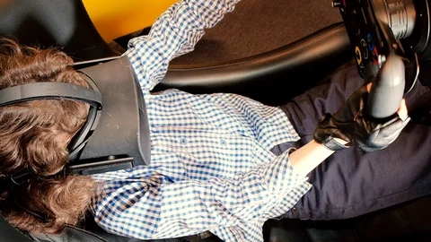 A child holding a gaming computer wheel getting experience using VR-headset glas Stock Footage 111912144