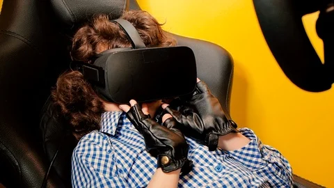 A child holding a gaming computer wheel getting experience using VR-headset glas Stock Footage 111912214