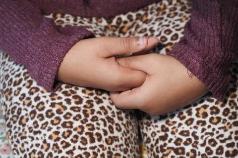 Child holding hands while sitting on a patterned surface 스톡 사진