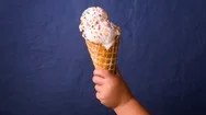 Child Holding Melting Ice Cream Cone In Hand On Blue Background Cinemagraph Stock Footage