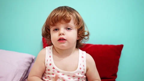 Child holding a red marker playfully under nose against vibrant blue wall Video stock 329256568