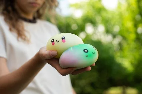 Child holding two smiling dumpling squishy toys in open hands. Stock Photos