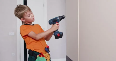 Child holds electric screwdriver studying rotating mechanism Stock Footage 323970037