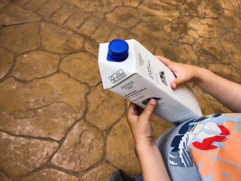 A child holds a milk package from Granjas de Mallorca, enjoying a refreshing Stock Photos