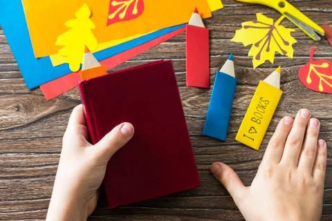 Child holds multi-colored bookmarks origami pencil made of paper. Stock Photos