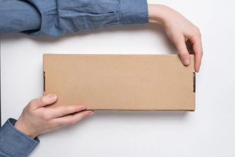 Child holds rectangular craft paper box on white background. Parcel delivery  스톡 사진