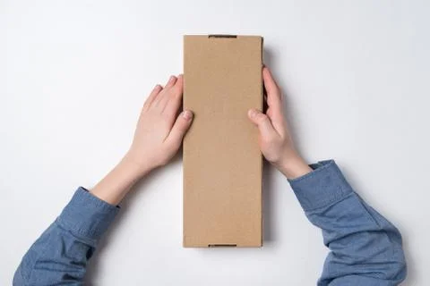 Child holds rectangular craft paper box on white background. Parcel delivery  写真素材