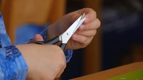 The child holds scissors in her hands and cuts. Materials for crafts on the Stock Footage 75631380