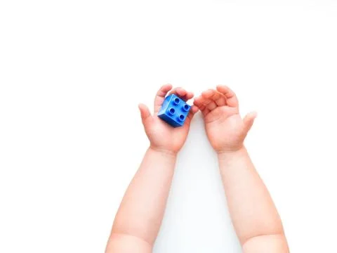 Child is holidng blue constructor block in fist. Kid's hands with toy on whit Stock Photos