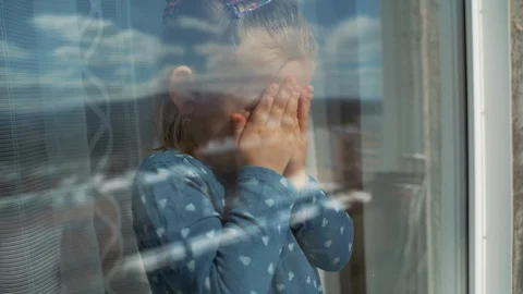 The child is at home in isolation outside the window, crying and wants to play Stock Footage 128041048