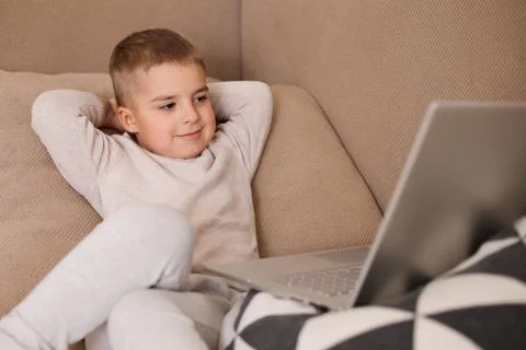 Child at home watching cartoon on the computer. Little boy and a laptop. Mode Stock Photos