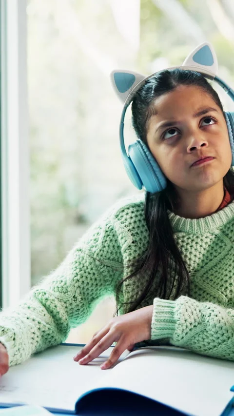 Child, homework and thinking in house with headphones, music and writing answer Stockbeeldmateriaal 338091539
