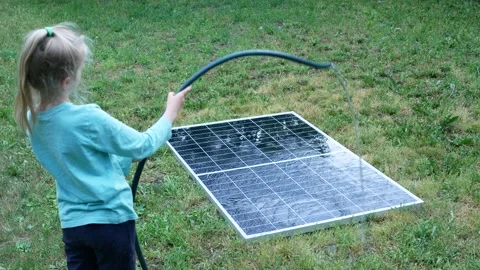 The child hoses water to the solar panel and cleans it of dust and dirt Vídeos de archivo 197340468