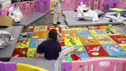 Child immigrant playing on floor at temporary processing facility in Donna Texas Stock Footage 151251783