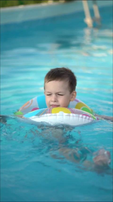 Child in inflatable ring enjoying a bright summer day in the swimming pool. Stock Footage 342282462