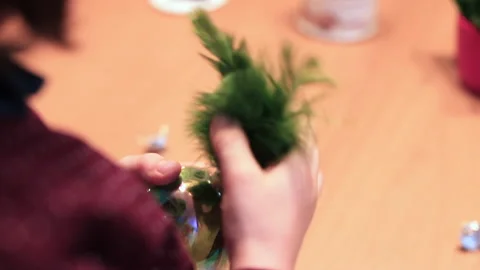Child inserts feather in transparent ball fingers preparation props for holiday Stock Footage 145801766