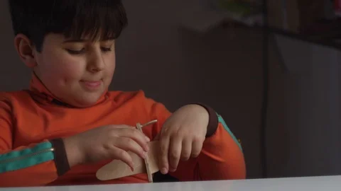 The child inserts wings into the wooden model of the aircraft Stock-Footage 87569292