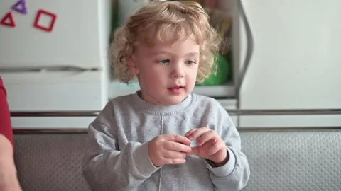 A child interacts with an adult while eating a snack at a kitchen table. The Vidéo 337111176