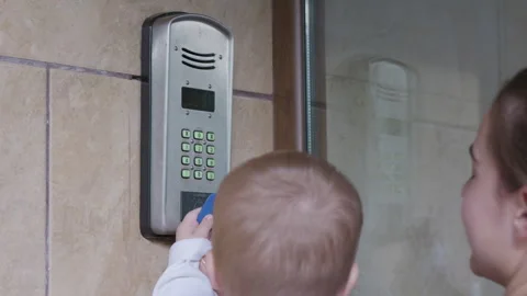 Child interacts with a digital door entry system, pressing buttons on the keypad Stock Footage 341335105